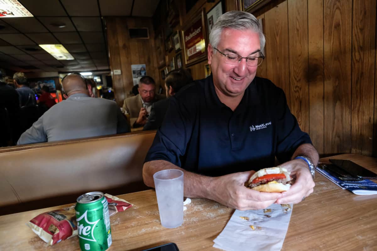 Gov. Eric Holcomb smiles before taking a bite out of his burger at The Brick in Jonesville, Ind., Thursday, Aug. 8, 2019. Mike Wolanin | The Republic