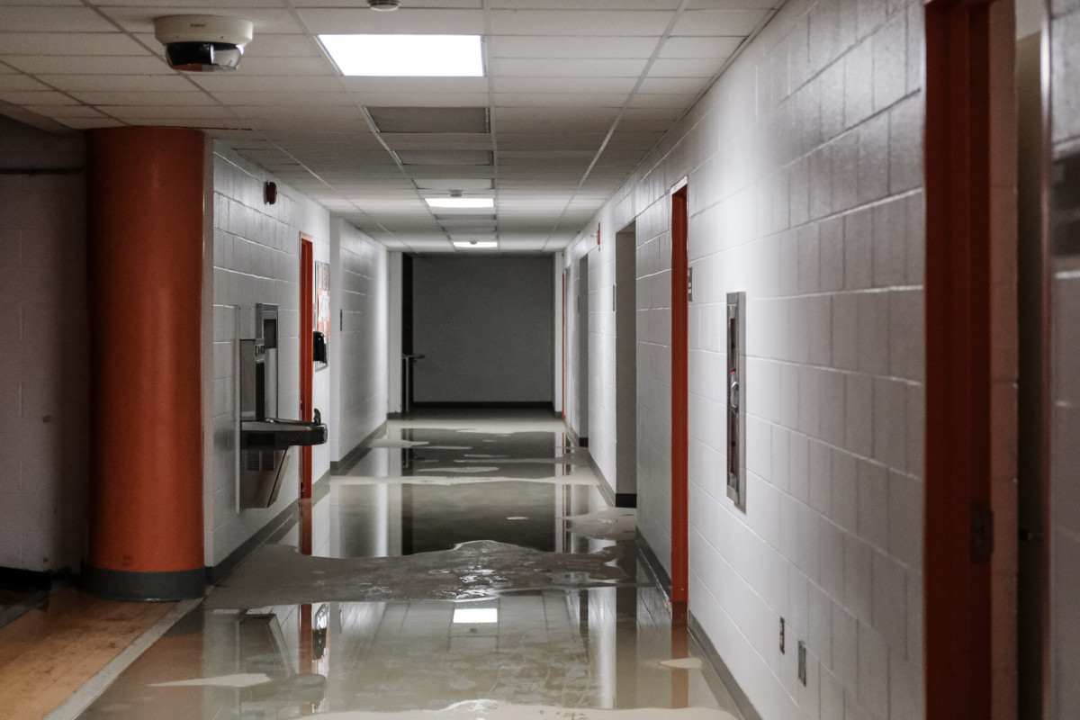 Puddles of standing water are seen in a hallway near the main gymnasium at Columbus East High School in Columbus, Ind., Monday, June 21, 2021. Workers from Roberts Cleaning Service and school official were on hand to assess and clean up the damage caused by flooding from the thunderstorms over the weekend. Mike Wolanin | The Republic