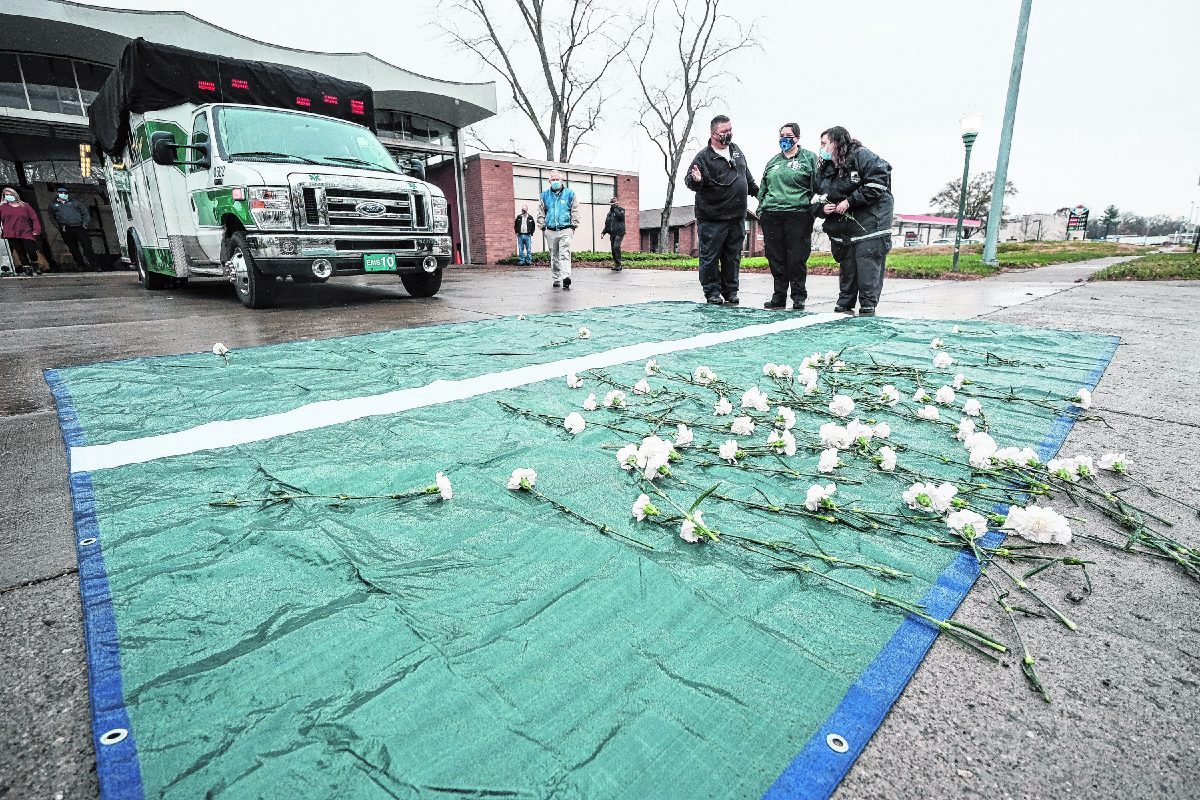Carnations rest on a tarp in front of an ambulance carrying the remains of Columbus Regional Hospital paramedic/EMT Scott Gordon at the Columbus Regional Hospital EMS Base in Columbus, Ind., Saturday, Nov. 21, 2020. Gordon contracted COVID-19 during his line of work as a paramedic/EMT on a Columbus Regional Health ambulance. He died on Nov. 15 after and eight-day battle with COVID-19. Mike Wolanin | The Republic