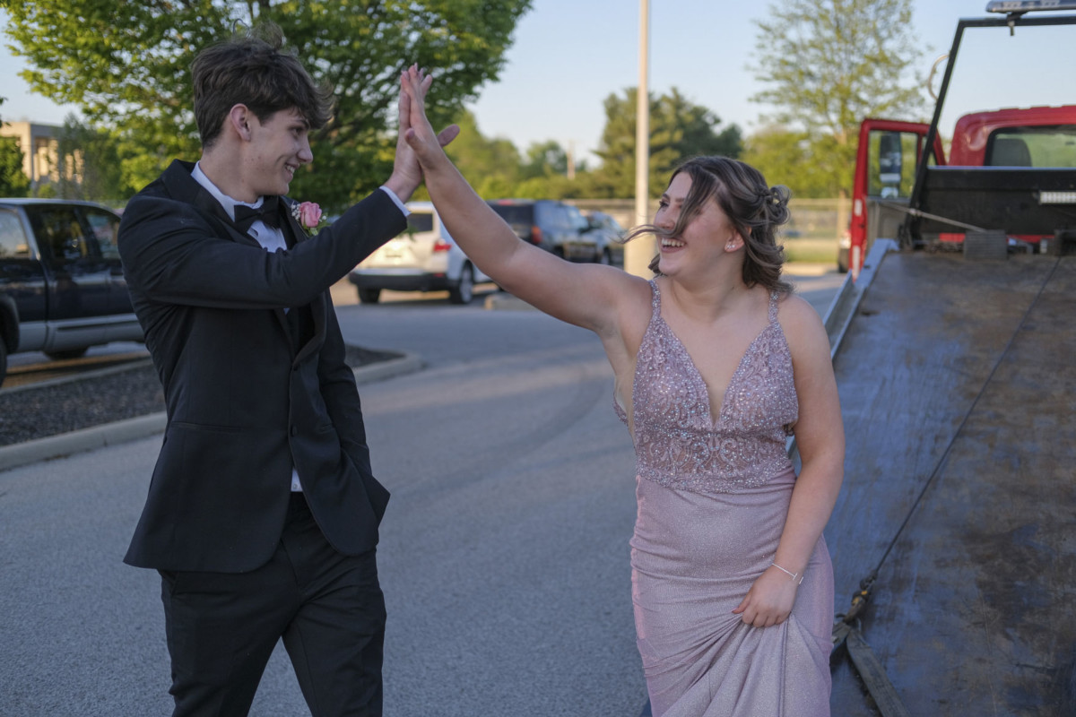 Columbus North students Kyle Greathouse, left, and Aleiah Campbell high five after arriving for prom on the back of a wrecker in the parking lot at Columbus North High School in Columbus, Ind., Saturday, May 1, 2021. Mike Wolanin | The Republic