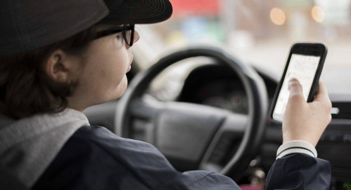 132950257_web1_Teen-scrolling-through-phone-in-drivers-seat-iStock-503483294-1068x580